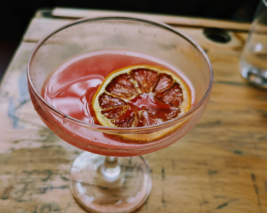 Cocktail with a blood orange slice in a glass on a wooden surface